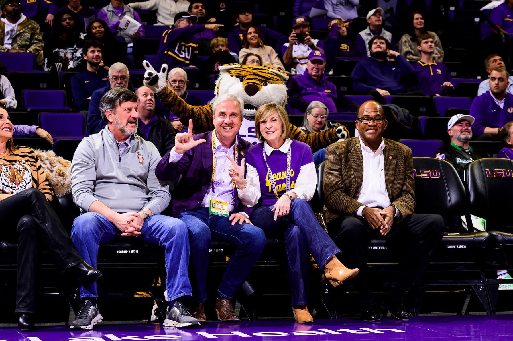 LSU President, Wade Rousse, attending a LSU basketball game holding up an L.